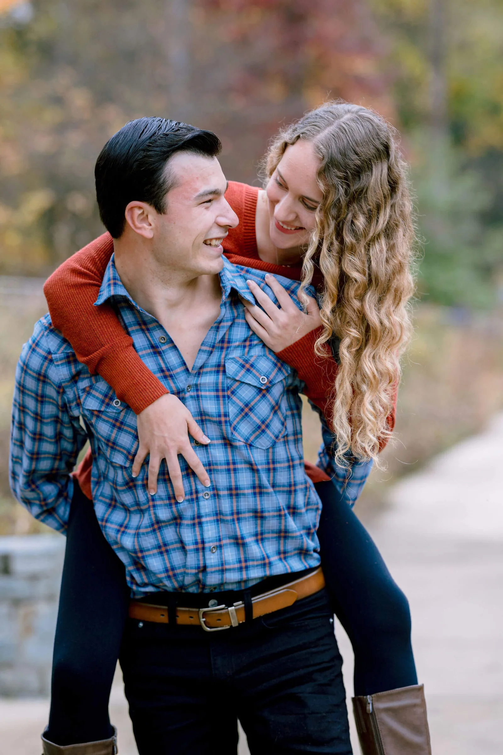 Man carrying his partner during a playful fall engagement portrait