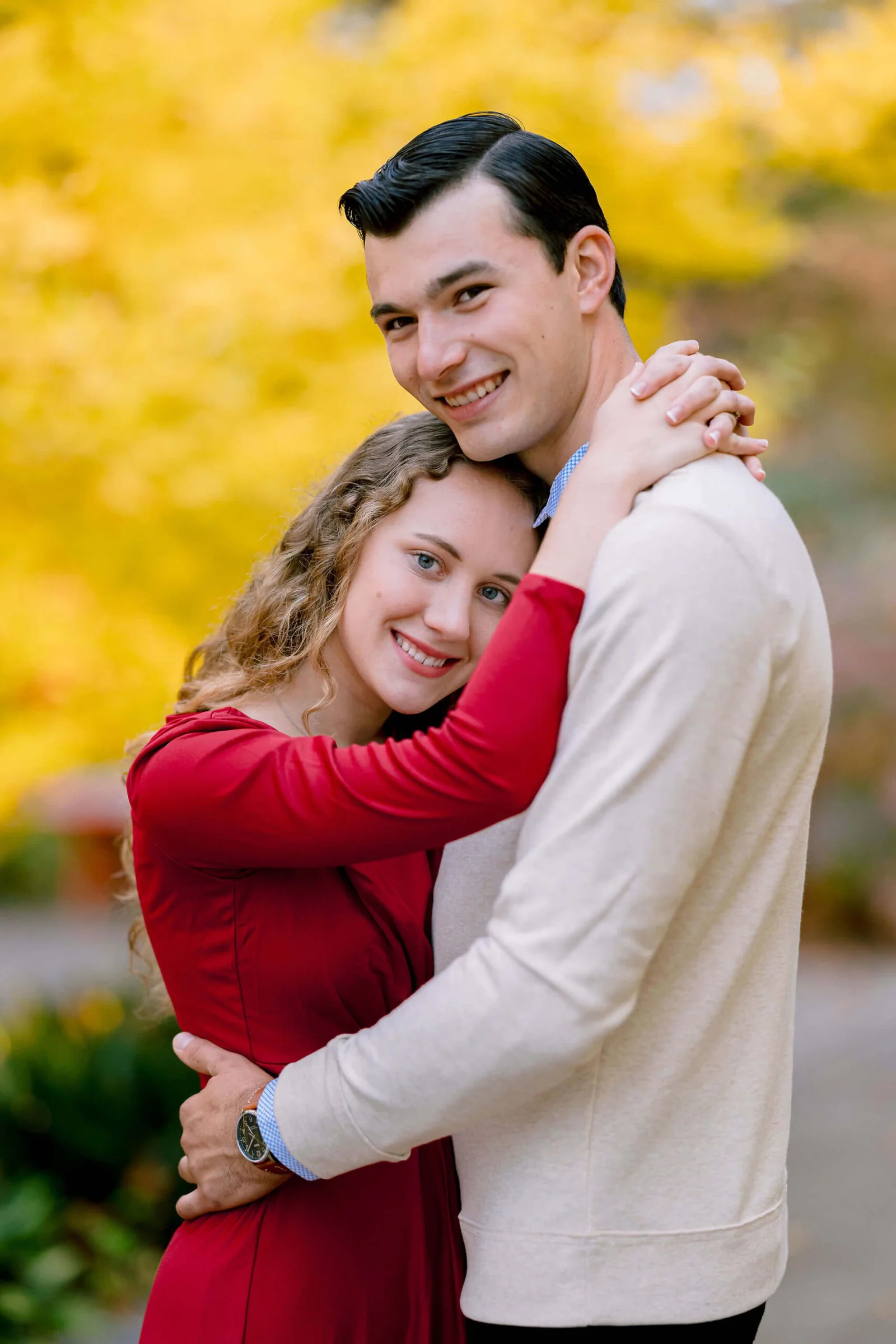 Couple sharing a close embrace beneath yellow autumn leaves