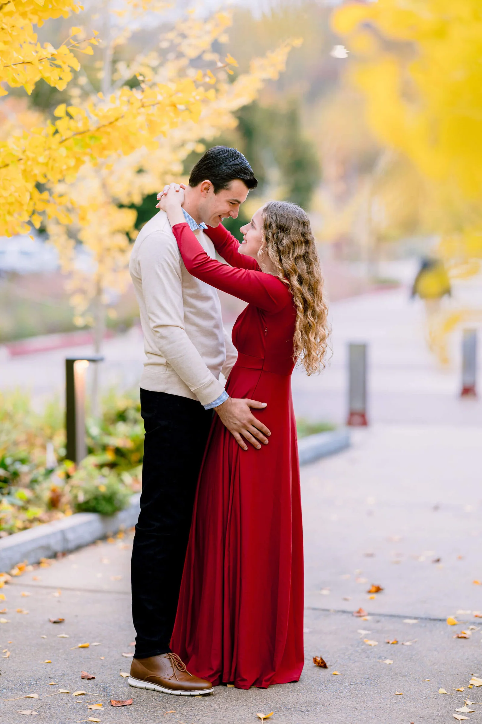 Couple embracing in front of a brilliant yellow autumn tree