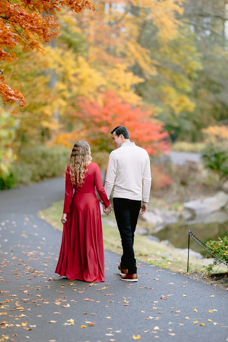 Couple walking along a path lined with colorful autumn trees