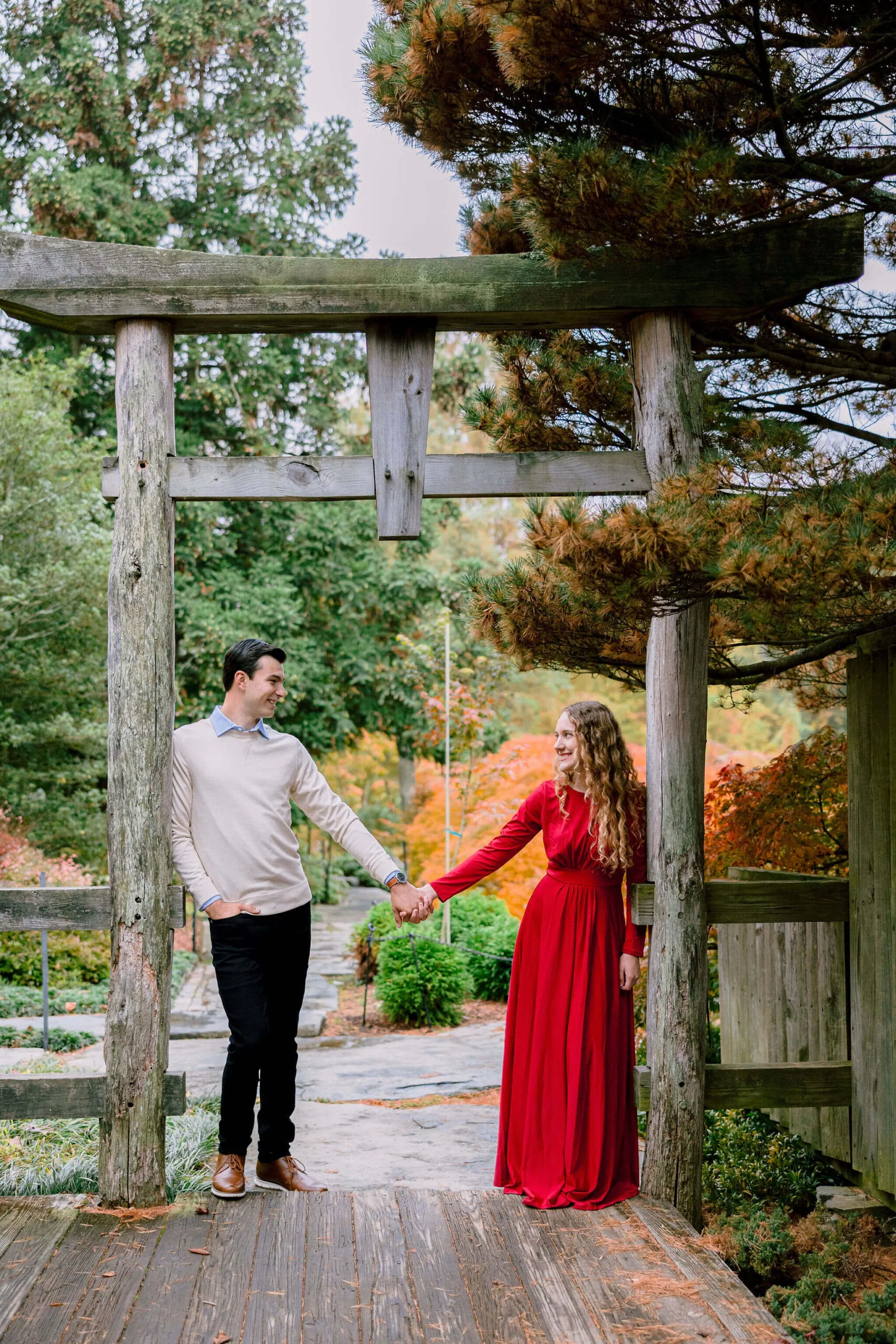 Couple holding hands beneath a garden gazebo surrounded by fall foliage