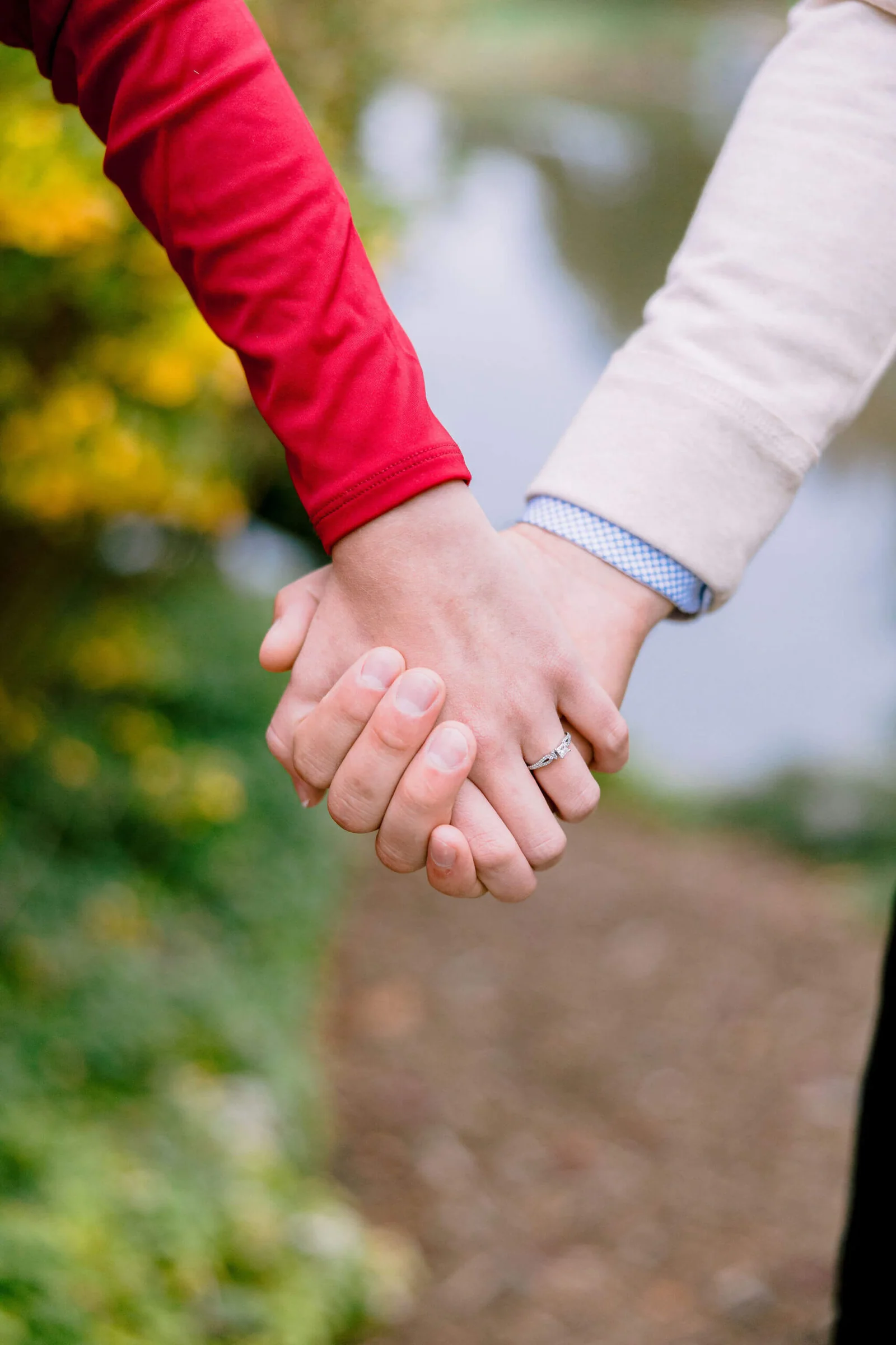 Close view of an engaged couple holding hands during their fall session