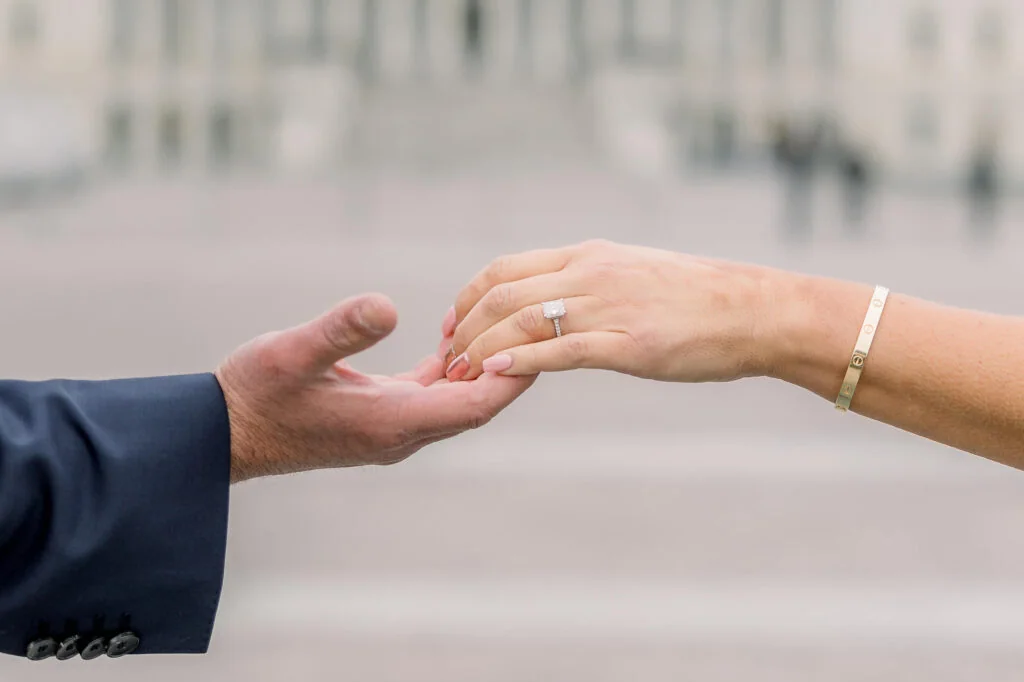 Engaged couple holding hands and showing an engagement ring