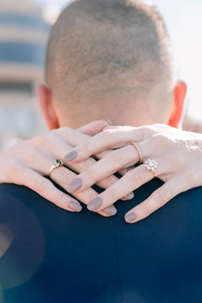 Couple embracing with wedding and engagement rings visible