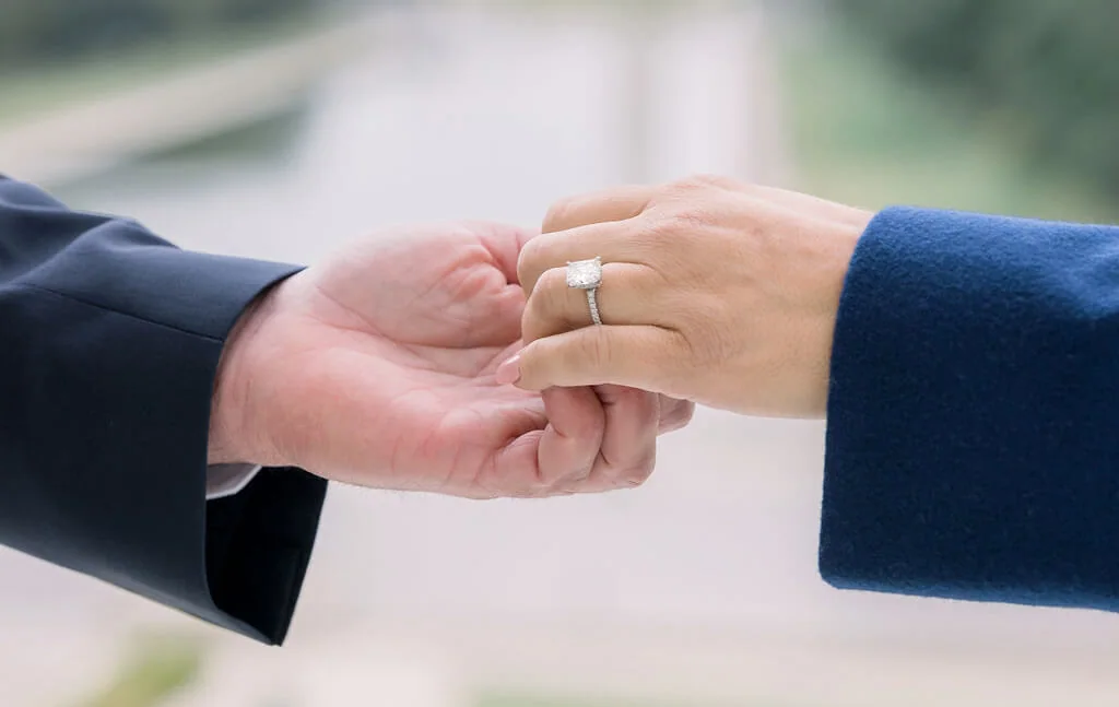 Couple holding hands with an engagement ring near the Lincoln Memorial
