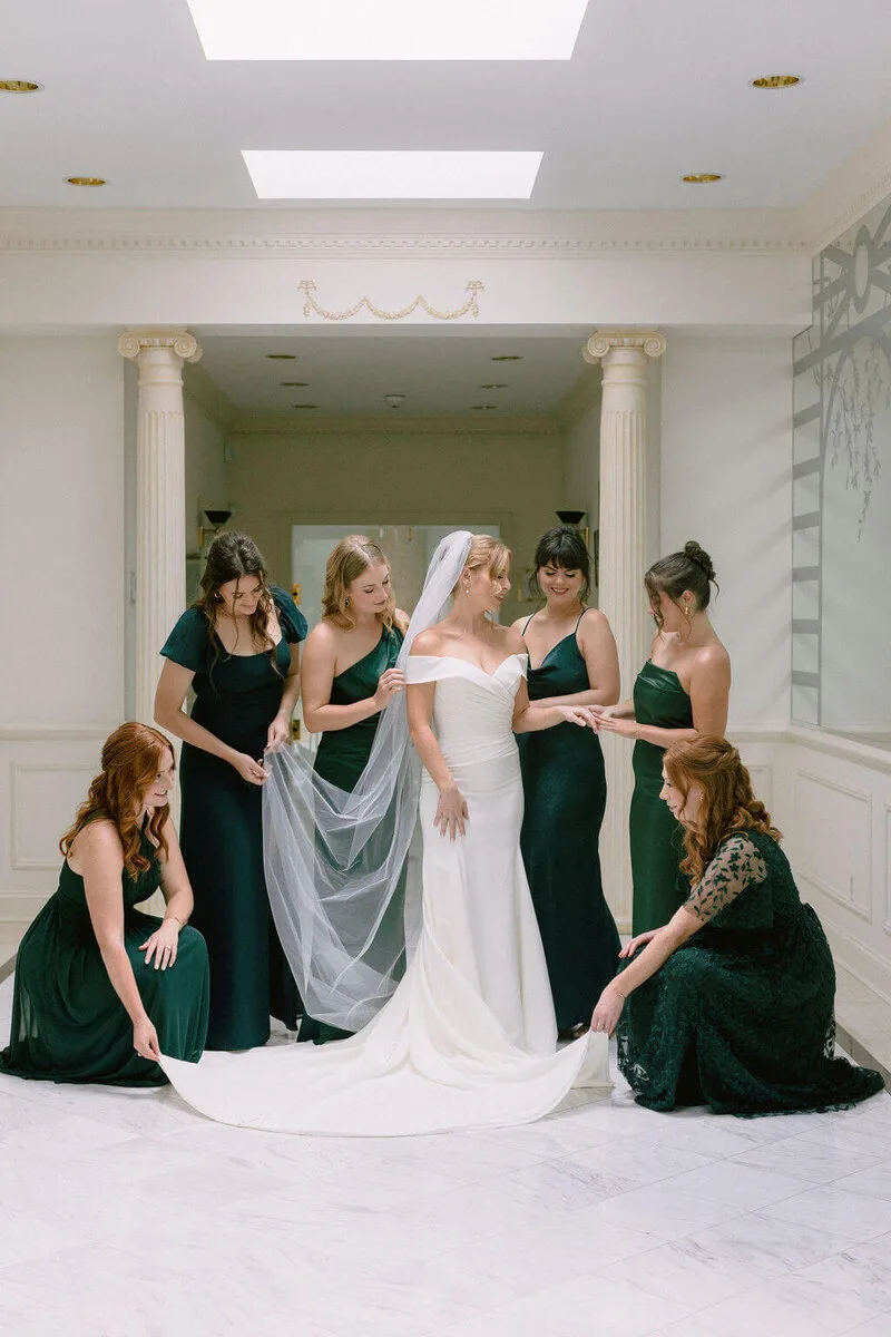 Bridesmaids sharing a first look in elegant green dresses
