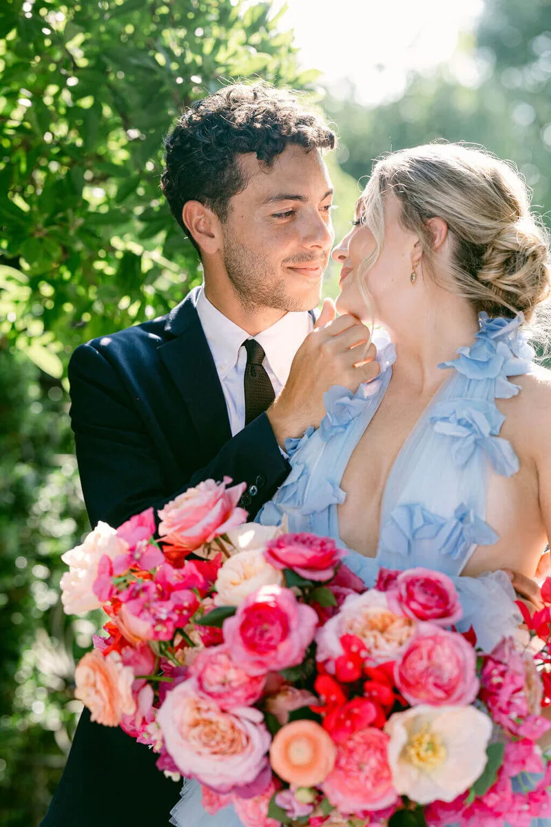 Wedding couple holding a colorful bouquet beneath a tree