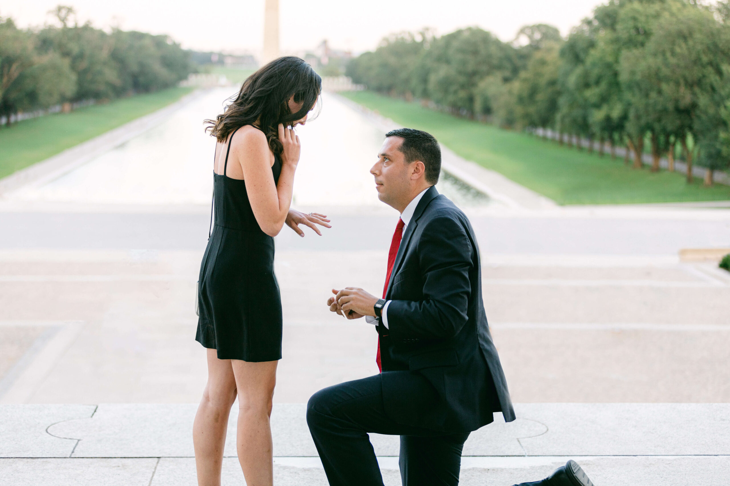 Engagement moment captured by Get Ready Photo at the Lincoln Memorial in Washington DC, with a man proposing on one knee to a surprised woman, reflecting the romantic spirit of the city
